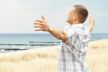 Man at the seaside spreads his arms
