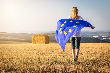 Woman walking with waving european union flag in countryside