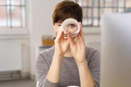 Young woman uses a rolled up sheet of paper as binoculars