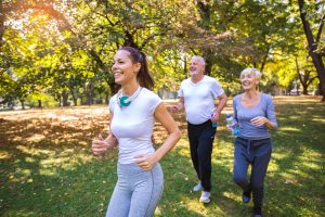 Senior man and woman and young female instructor running in a park