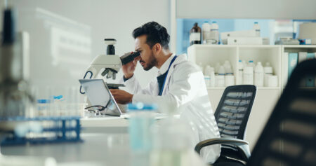Scientist, sample and man with microscope in lab for clinical trial, virus study and experiment. Science, innovation and employee with equipment for medical research, vaccine development and analysis.