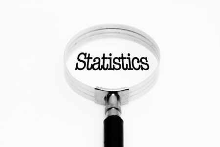 The word "Statistics" under a magnifying glass against a white background.